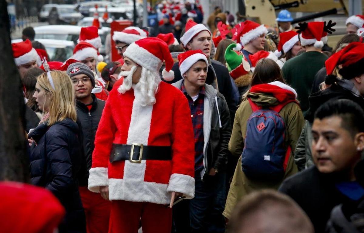 SantaCon revelers wait in line to enter a bar at last year’s event in New York. SantaCons are happening in cities across the country (including Fresno) Saturday, Dec. 9.