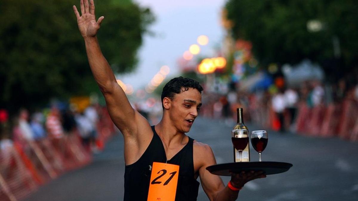 
In this 2009 file photo, Hialys Sousa, representing the Rio Grill, waves to supporters as he passes the Visalia restaurant, turns the corner and heads for the finish line during the men’s full service Waiters Race.
