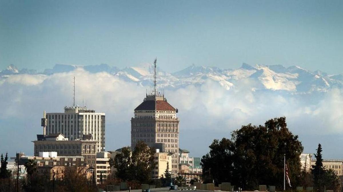 The downtown Fresno skyline seen below snow caps the Sierra Nevada mountains and clouds along the foothills.