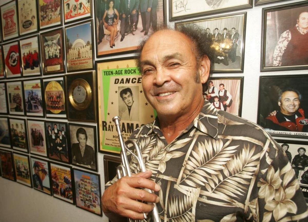 Ray Camacho stands in August 2006 before a wall full of photographs that have memories from four decades of The Ray Camacho Band.