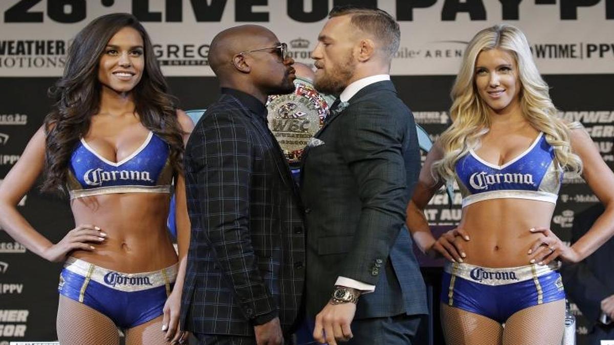 Floyd Mayweather Jr., center left, and Conor McGregor pose for photographers during a news conference Wednesday in Las Vegas. The two fight tonight in a bout that can be seen at Edwards theaters and on pay-per-view.