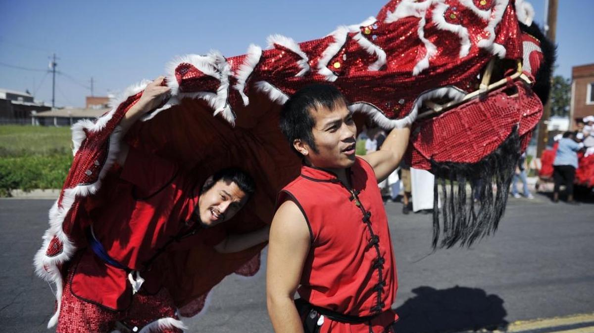 Justin Chan, left, peeks out with Luan Nguien, right, both with John Cho’s Lion Dance Team, as they prepare for the start of the annual Chinese New Year Parade last year. This year’s parade (the 16th annual) is on Saturday, March 5.