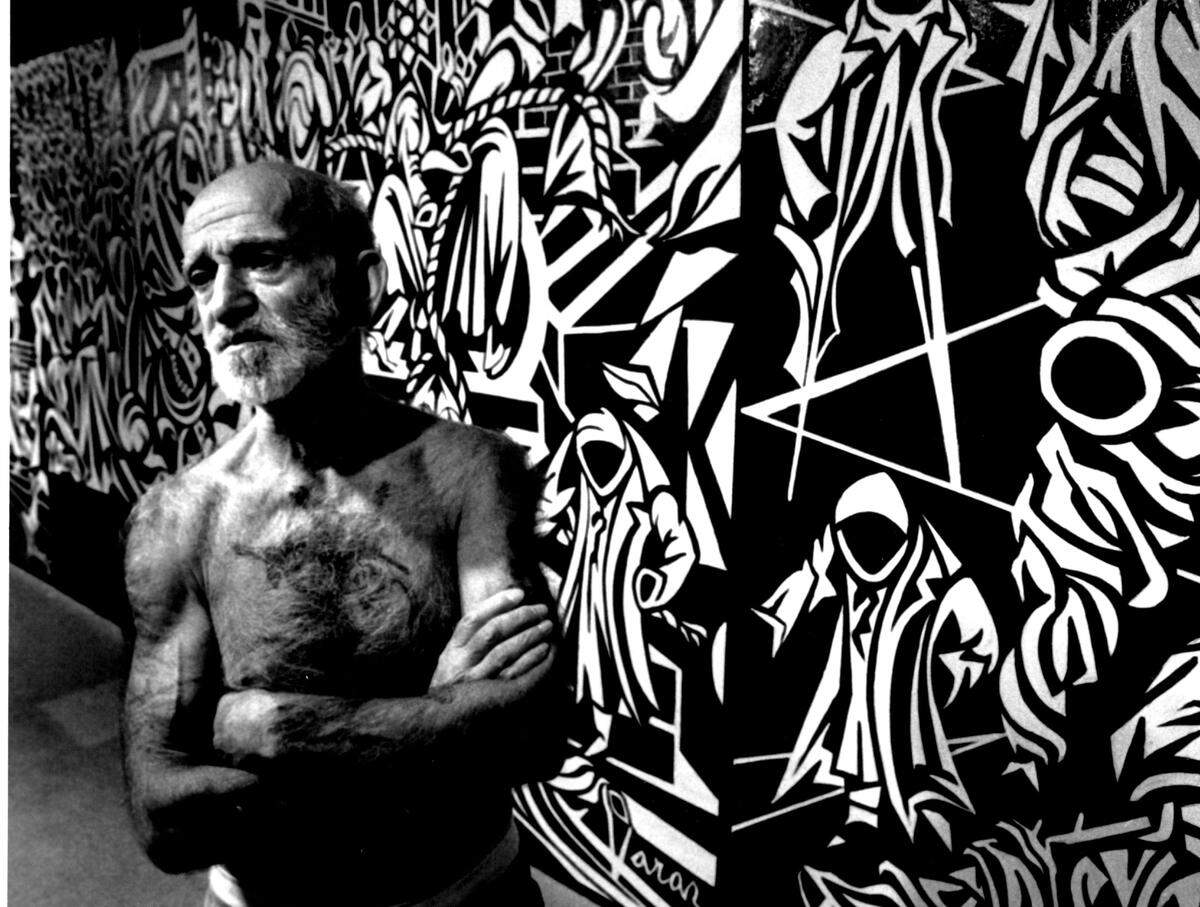 Varaz Samuelian and a painting entitled “Nuetron Bomb” are shown in this file photo from 1990. The painting consisted of panels totaling 30 feet in length.