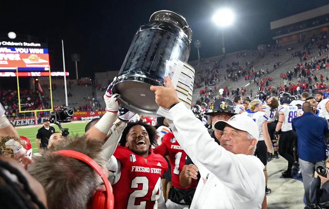 Fresno State coach Jeff Tedford, right, hoists the milk can trophy after the Bulldogs beat Boise State 37-30 Saturday, Nov. 4, 2023 in Fresno.