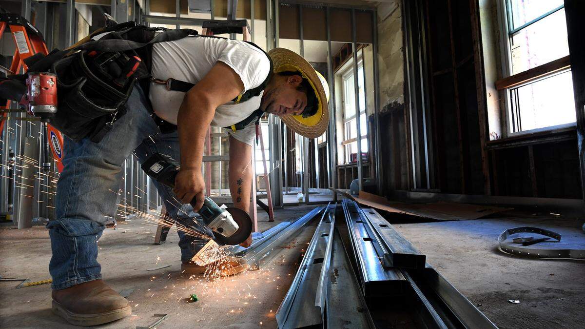 Construction worker Cesar Loyola cuts sheet metal studding for an apartment ceiling on the 5th floor of the historic Hotel Fresno, which is undergoing renovation into a 79-unit affordable housing complex, Wednesday July 15, 2020. The work has been slowed by the pandemic in that fewer workers are allowed on site at one time.