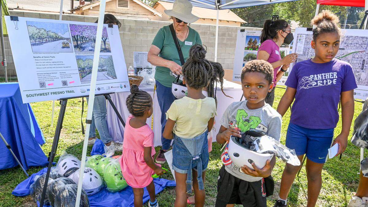 Kids receive free bike helmets from representative from the Southwest Fresno Bike Trail program during a 2022 community event held at Maxie L. Parks Community Center in southwest Fresno.