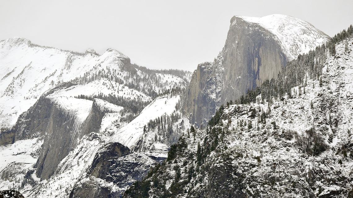 Half Dome and surrounding peaks loom over Yosemite Valley shrouded in snow, Tuesday, Dec. 4, 2018.