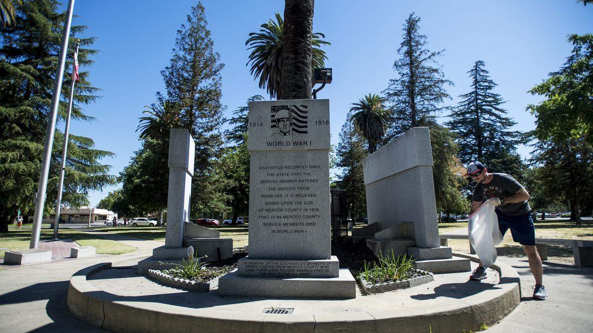 Caleb Henke, 25, of Merced, collects trash from around the Veterans Memorial during a park clean up at Courthouse Park, located at 21st Street and N Street in Merced, Calif., Thursday, July 14, 2016.