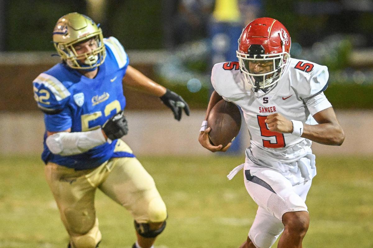 Sanger’s Marquis Cropper, right, dashes out of the reach of Clovis’ Jaydon Mendiola on a run to the outside during their game at Lamonica Stadium in Clovis on Friday, Aug. 25, 2023.
