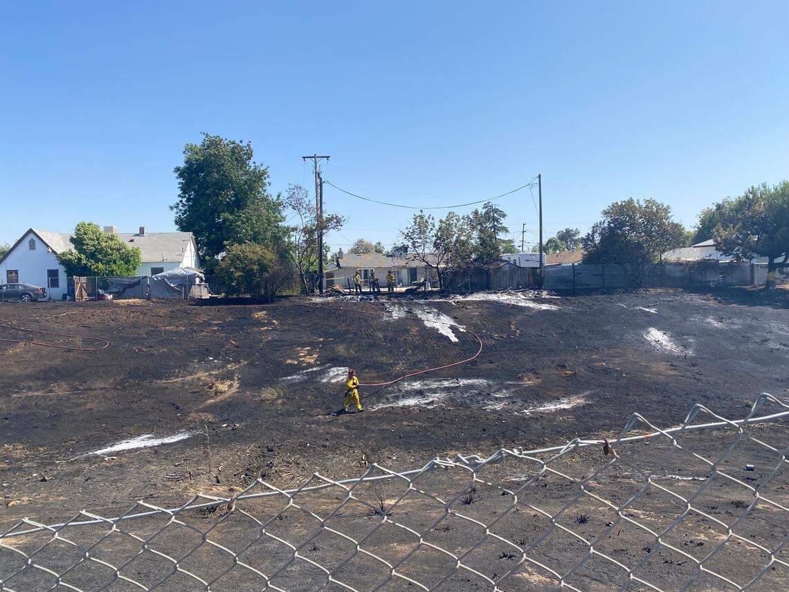 Fire crews work to douse hot spots after a grass fire was started on Saturday, June 21, 2025 in Fresno, California.