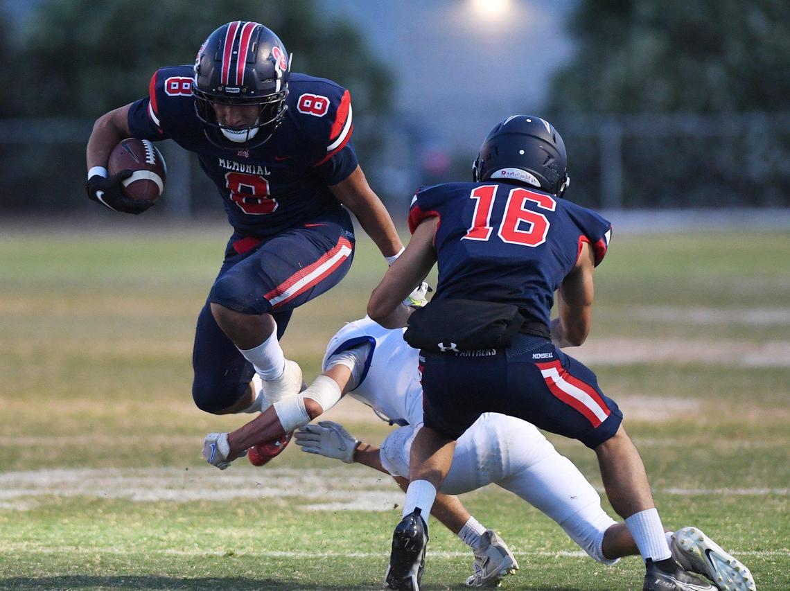 San Joaquin Memorial’s Brandon Ramirez, left, leaps over Madera’s Chris Marquez’ tackle, background, Friday, April 30, 2021 in Fresno.