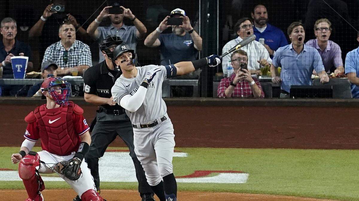 New York Yankees’ Aaron Judge follows through on a solo home run, his 62nd of the season, as Texas Rangers catcher Sam Huff, left, and umpire Randy Rosenberg, rear, look on in the first inning of the second baseball game of a doubleheader in Arlington, Texas, Tuesday, Oct. 4, 2022. With the home run, Judge set the AL record for home runs in a season, passing Roger Maris. (AP Photo/Tony Gutierrez)