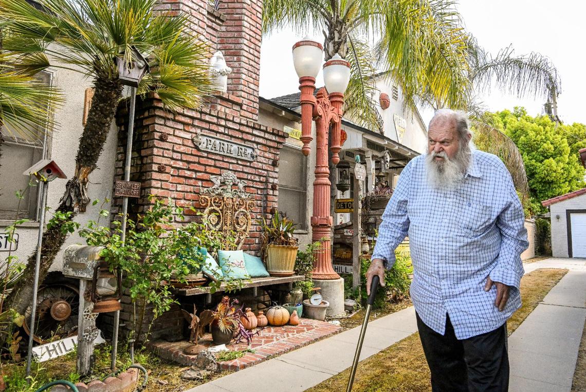 Jim Williams walks alongside his home decorated with old street lights, signs and historical artifacts in the Fresno High area where he has lived for 47 years.
