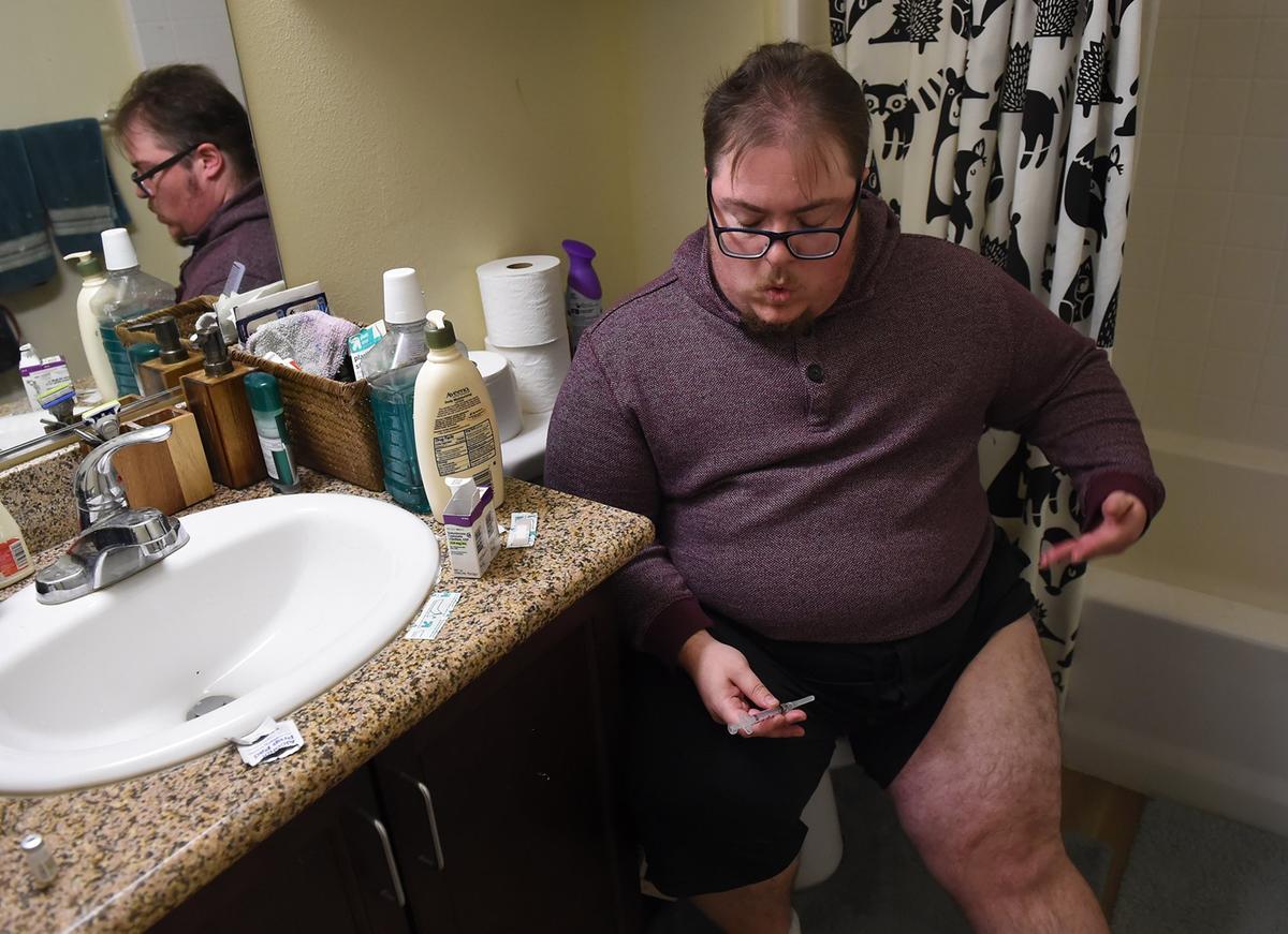 Jess Fitzpatrick, who has a hard time with needles, takes a deep breath before injecting himself with hormones at home Thursday, Nov. 8, 2018 in Fresno.