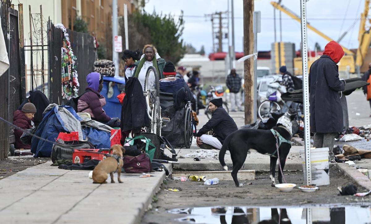 Homeless gather outside the Poverello House entrance on Santa Clara Street Friday, Dec 26, 2025 in Fresno.