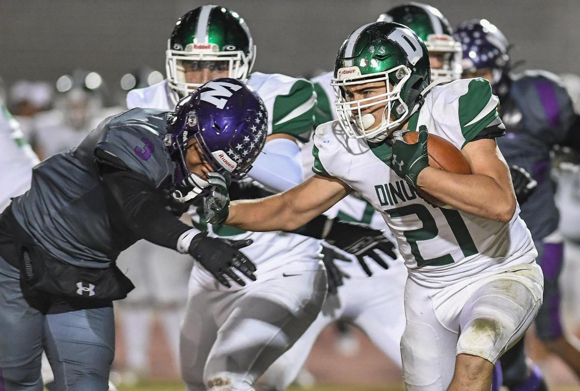 Dinuba’s Hector Gonzalez, right, tries to stiff-arm his way past Washington Union’s Ryan Brown Jr on a run in their Central Section Division II playoff game at Jesse Ventura Stadium in Easton on Friday, Nov. 4, 2022.