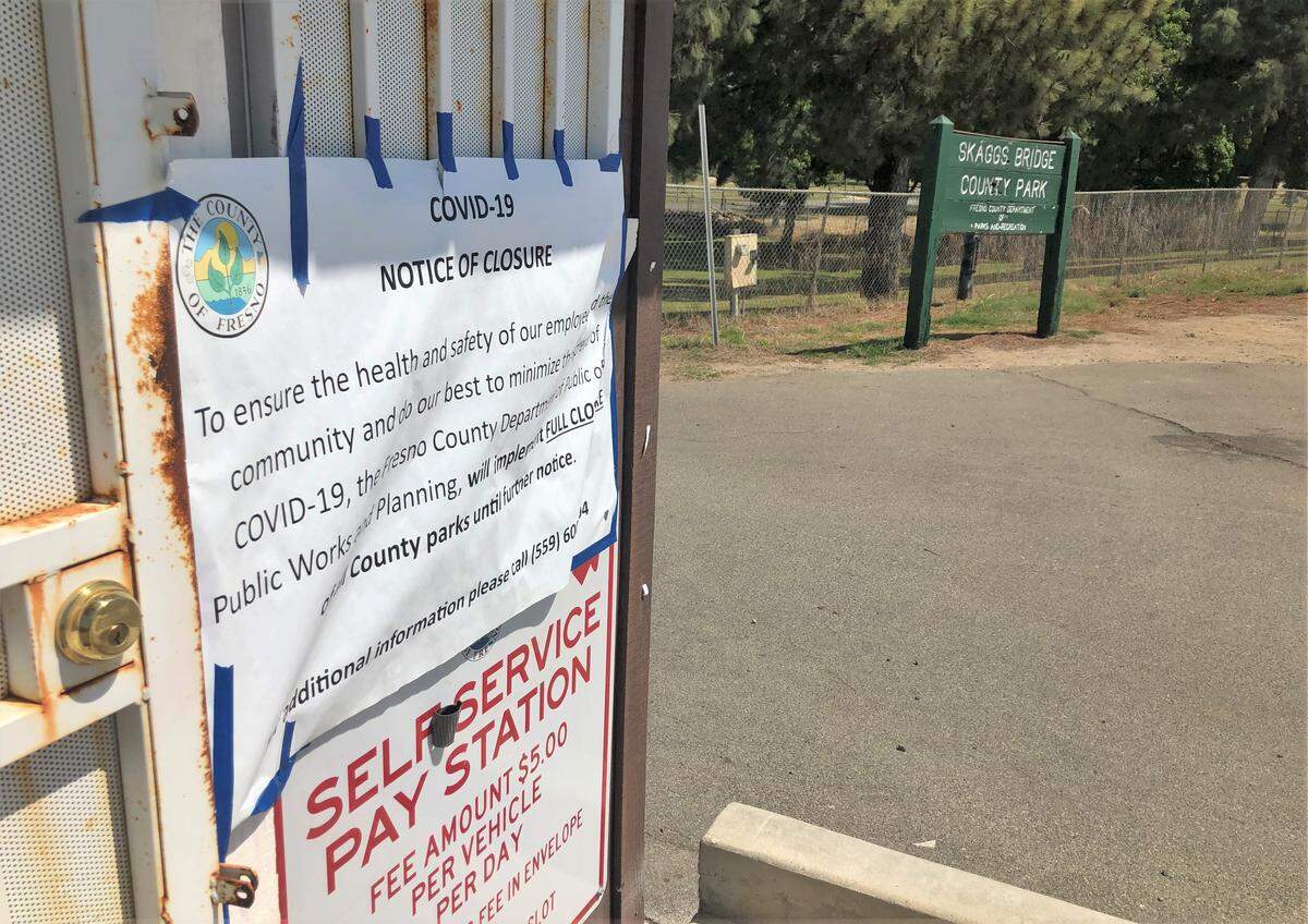 A sign taped to the self-service pay station at the entrance to Skaggs Bridge Park declares the Fresno County park closed as a precaution against the spread of the COVID-19 virus on Saturday, May 9. One family defied the closure order, seeking refuge from a hot afternoon by picnicking on the Fresno County side of the San Joaquin River.