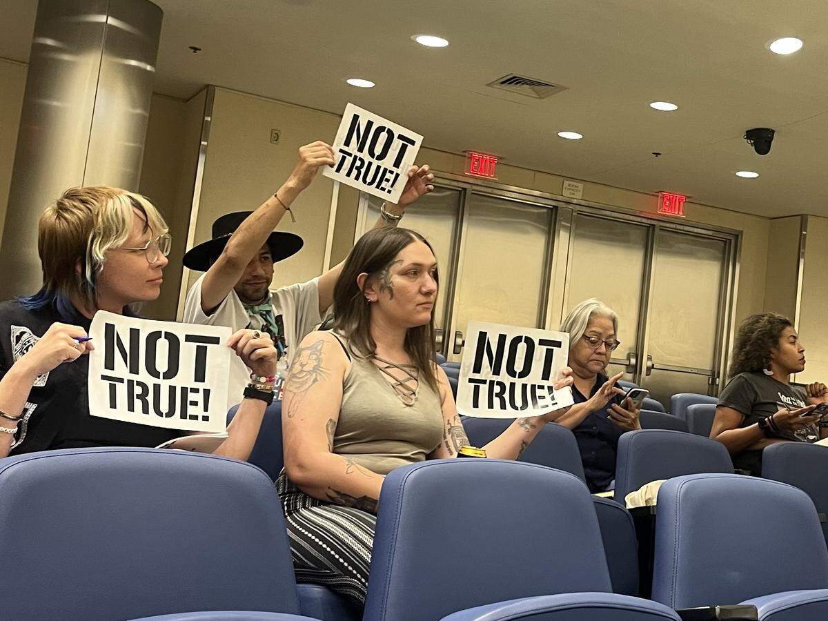 Members of the advocacy group Fresnans for a People’s Budget hold up signs that say “Not True!” at the Fresno police department’s first-ever public engagement meeting on its annual military equipment use report.