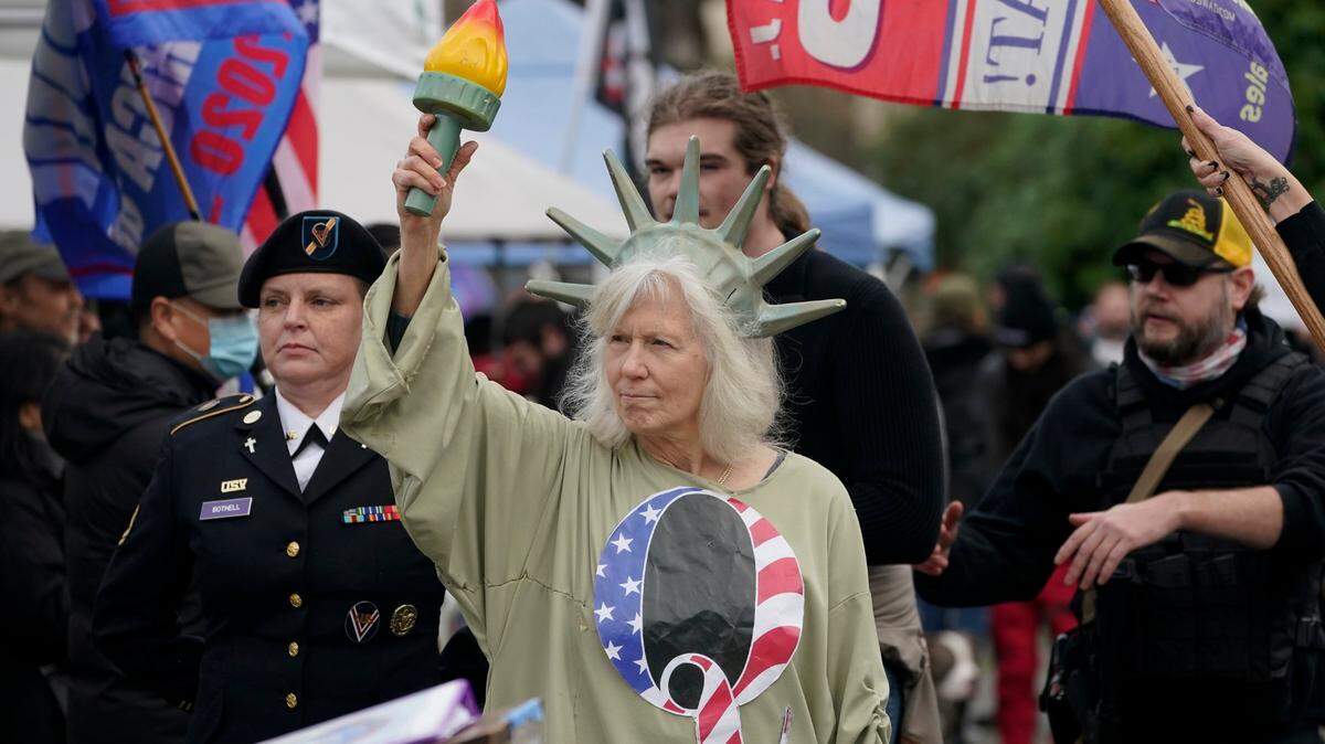 A person dressed as Lady Liberty wears a shirt with the letter Q, referring to QAnon, as protesters take part in a protest, Wednesday, Jan. 6, 2021, at the Capitol in Olympia, Wash., against the counting of electoral votes in Washington, DC, affirming President-elect Joe Biden’s victory. Several hundred people supporting President Donald Trump rallied at the Capitol Wednesday. (AP Photo/Ted S. Warren)