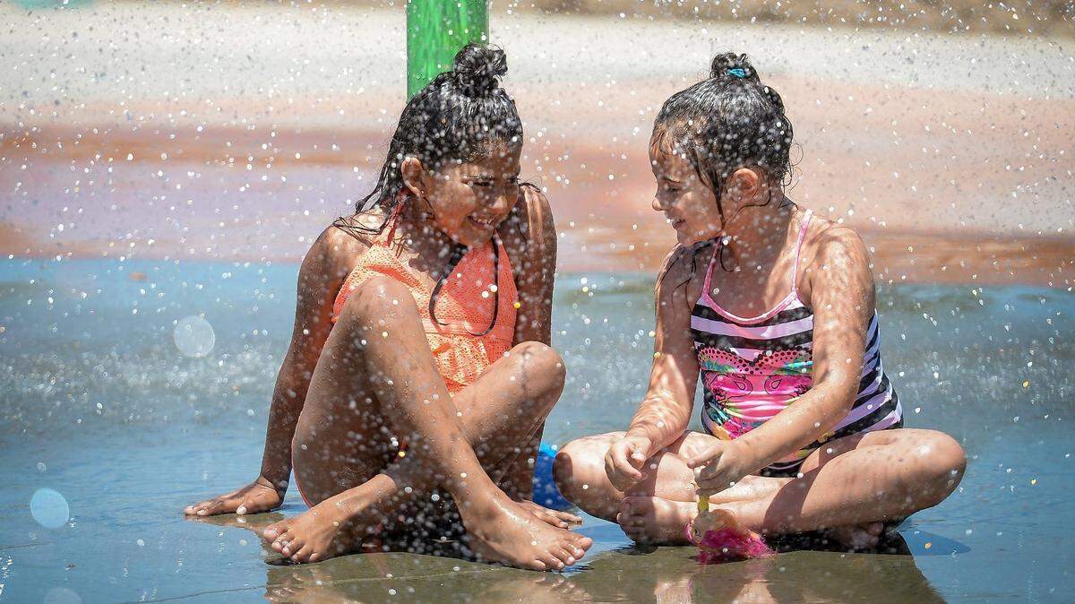 Dominique Mendoza, left, 8, and her godsister Gabriella Arredondo, 6, both of Fresno, cool off under a fountain in the splash park at Inspiration Park in northwest Fresno while celebrating a family member’s birthday as temperatures climb toward the triple digits on Saturday, June 23, 2018.