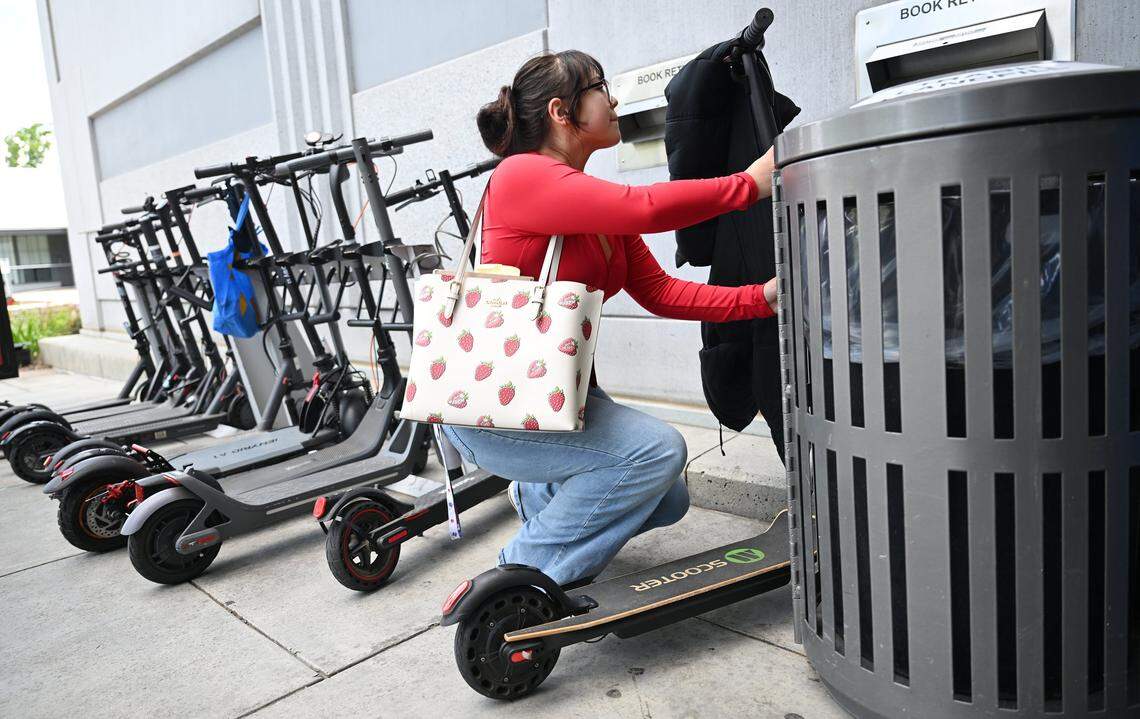 Lillyanna Beltran locks up her motorized scooter outside the Fresno State Library Monday, April 27, 2026 in Fresno. Beltran said she understands the safety concern but finds her scooter is very helpful in reaching classes on time and thinks specific scooter lanes could be a solution.