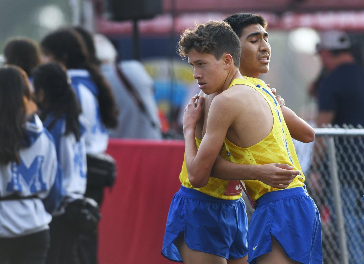 Clovis High’s Christopher Caudillo, foreground, first place finisher, hugs second place finisher teammate Nathaniel Avila, background, at the Central Section Boys DI cross country chamionship held at Woodward Park Thursday, Nov. 18, 2021 in Fresno.