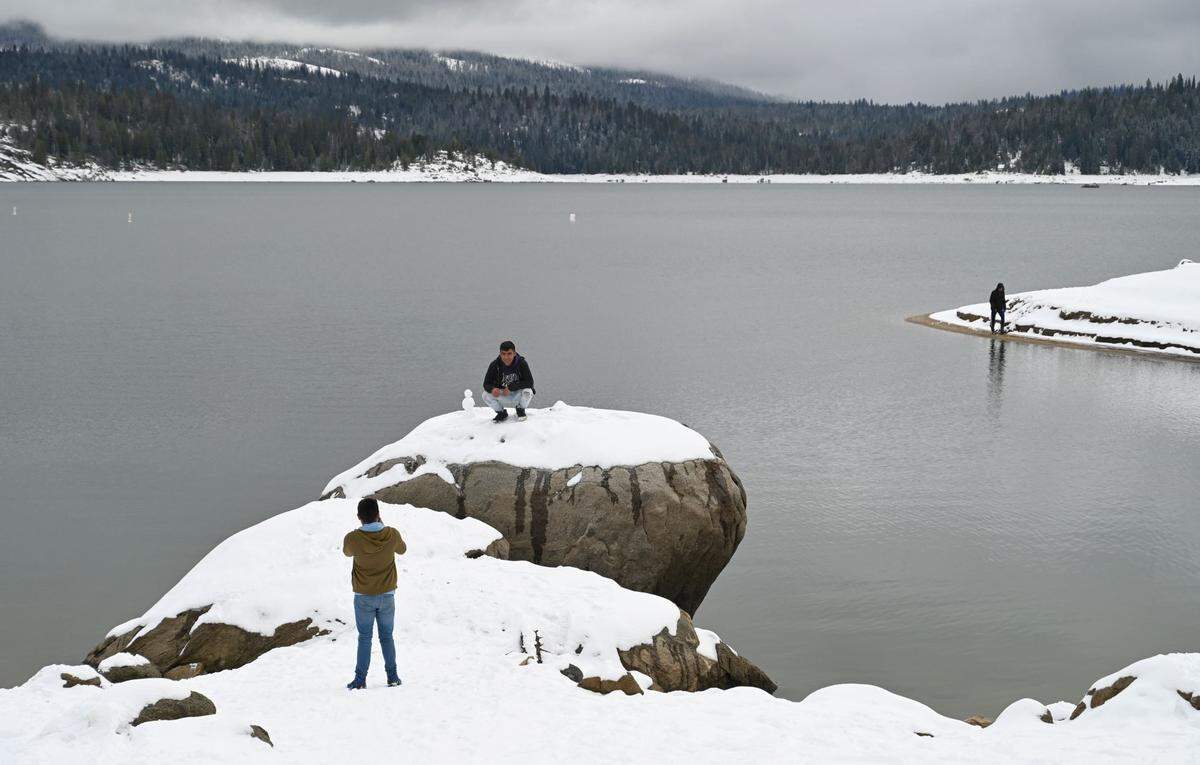 People enjoy the snowy scene, taking photos and building snowmen at Shaver Lake on Monday, Dec. 12, 2022.