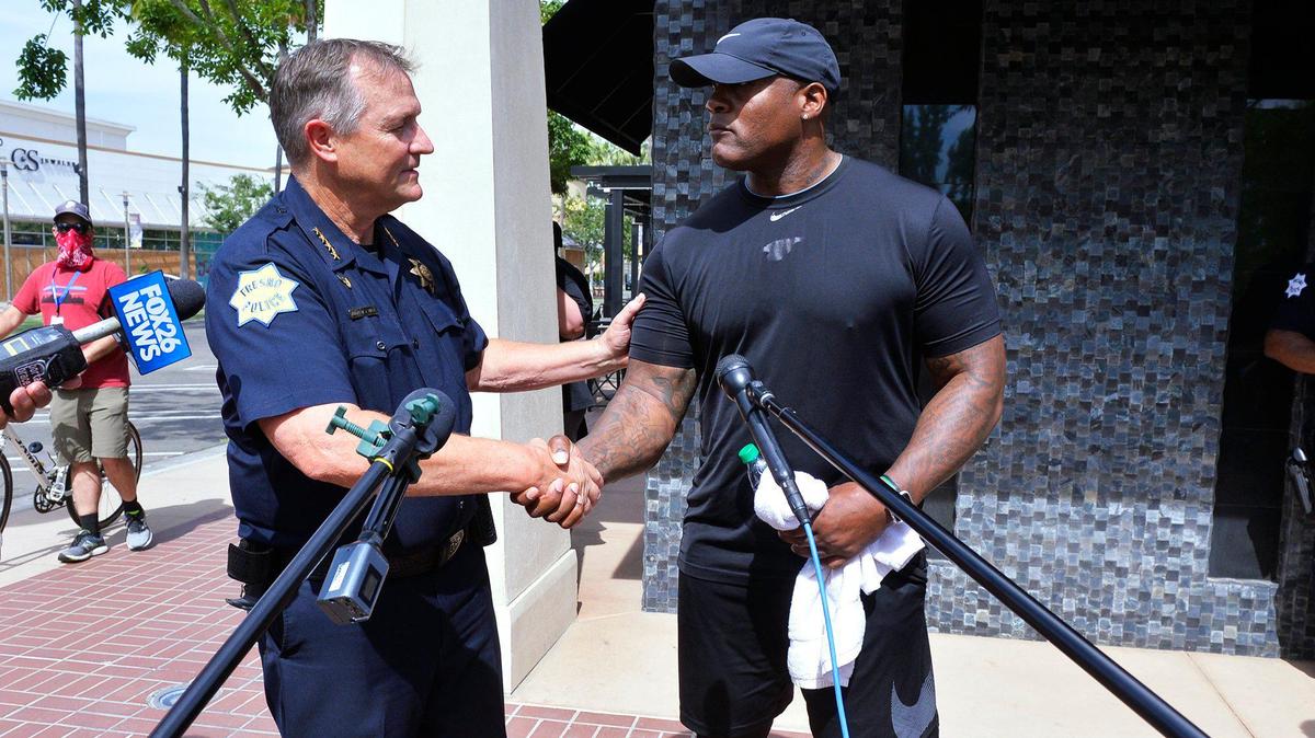 Fresno Police Chief Andy Hall, left, shakes hands with Chris Milton, right, before both spoke to the media at the Stand Against Violence gathering held in front of the Ruth’s Chris Steak House in River Park on Tuesday, June 2, 2020 in Fresno.