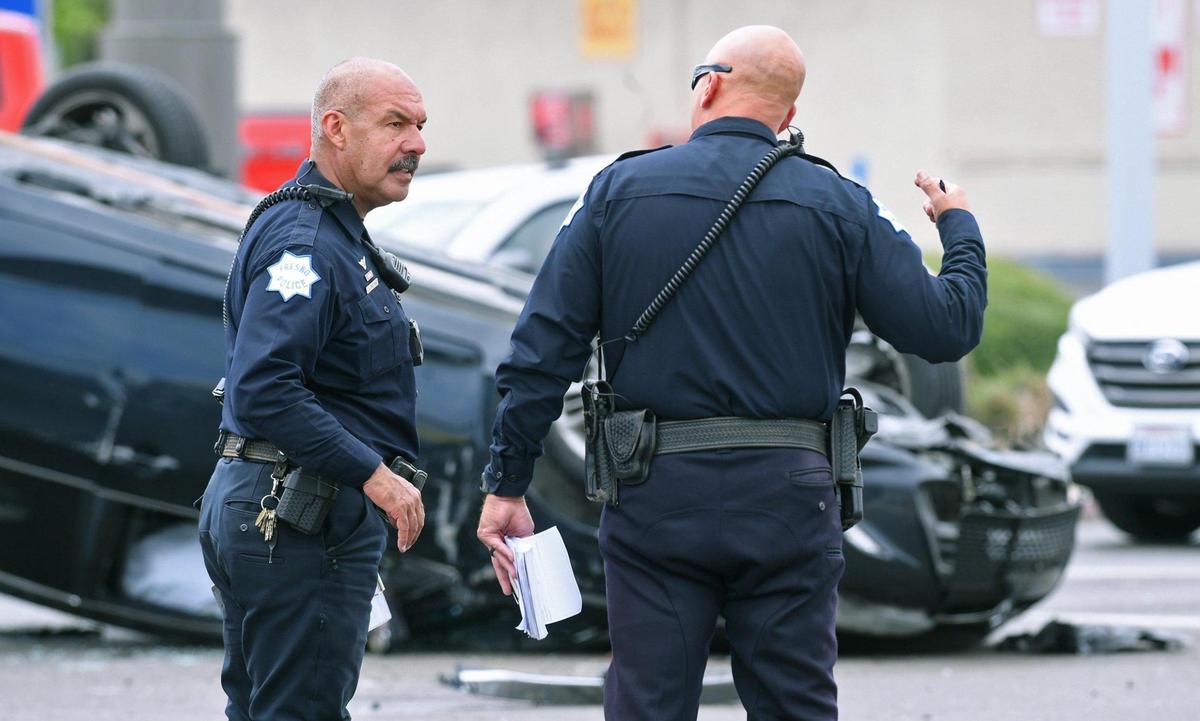 Officers investigate the scene of a three-vehicle collision including a rollover at the intersection of West Ashlan Avenue and Parkway Drive, Tuesday, April 19, 2022 in Fresno.