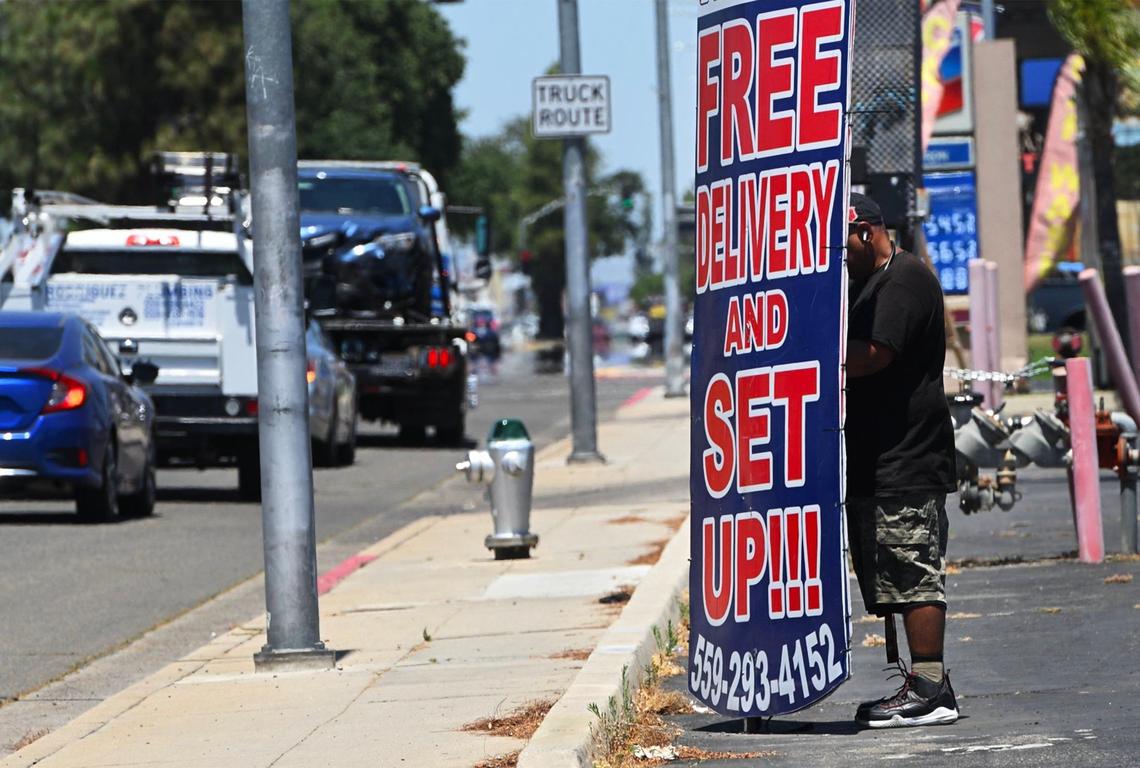 Gabriel Carpio works along Blackstone Ave. helping advertise for USA Furniture by twisting a sign back and forth all day long. Photographed Wednesday, May 29, 2024 in Fresno.