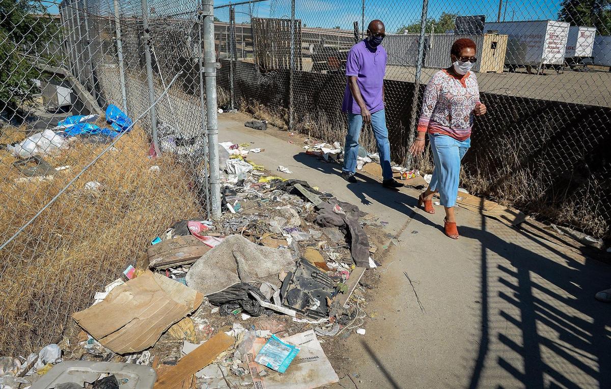 West Fresno advocates Deborah Darden and Bob Mitchell walk by a heap of trash near a bridge that at one time connected west Fresno to a popular park. Now Highway 41 has cut off west Fresno from that part of town and the park is now a dirt lot used to store moving trailers.