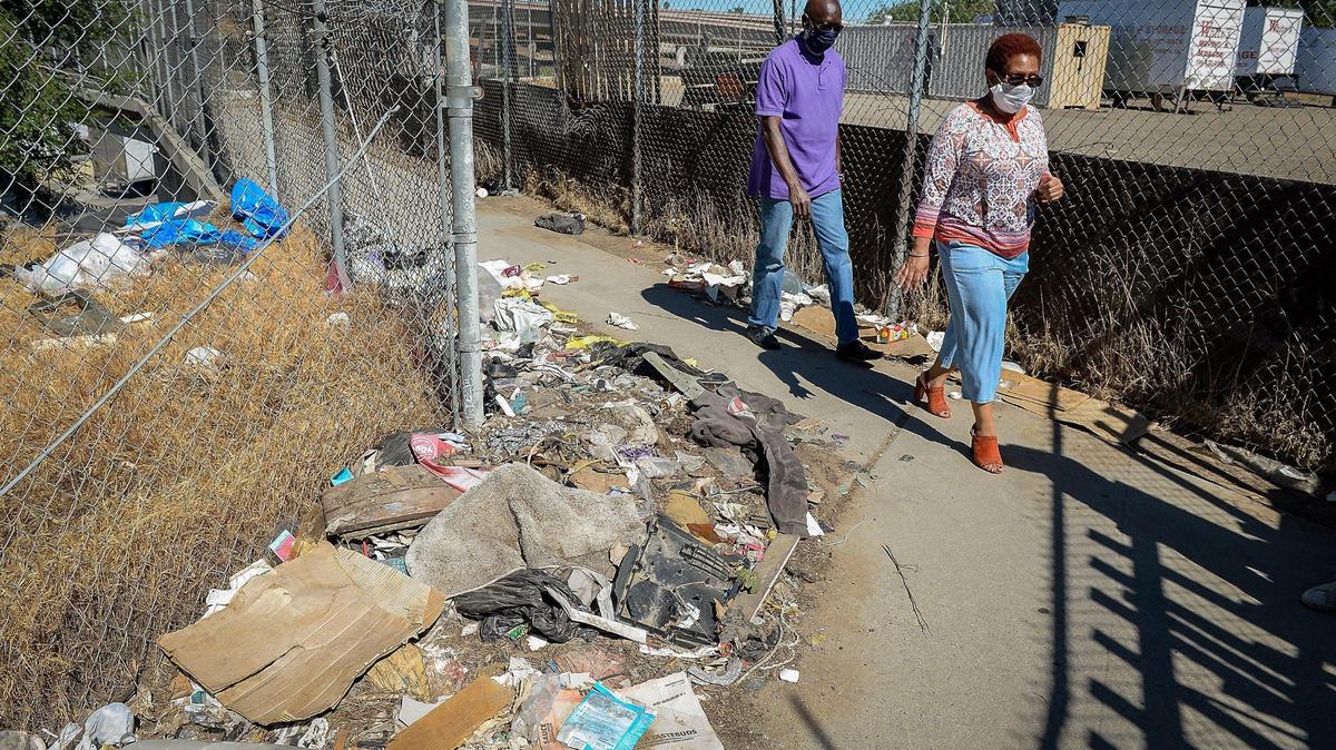 West Fresno advocates Deborah Darden and Bob Mitchell walk by a heap of trash near a bridge that at one time connected west Fresno to a popular park. Now Highway 41 has cut off west Fresno from that part of town and the park is now a dirt lot used to store moving trailers.
