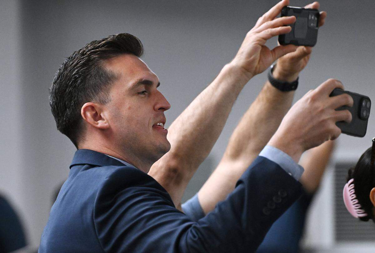 Johnathon Burrows, public information officer for Central Unified School District, joins parents taking photos of distinguished student athletes during the board meeting Tuesday night, May 26, 2026 in Fresno.