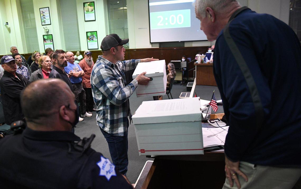 Boxes of complaints against mask and vaccine mandates are delivered to the Fresno Unified School Board by Norman Schuurman, center, as supporters stand in the background, left, during the board meeting Wednesday night, Feb. 16, 2022 in Fresno.