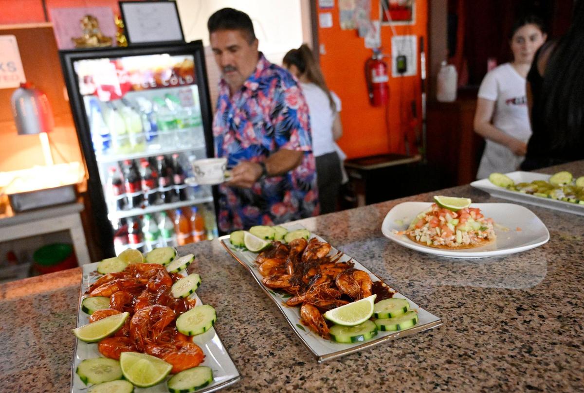 Raúl Godínez coloca muestras de la comida que se sirve en El Godinazo Fresno Centro Botanero, incluyendo langostinos y ceviche, el viernes 23 de junio de 2023.