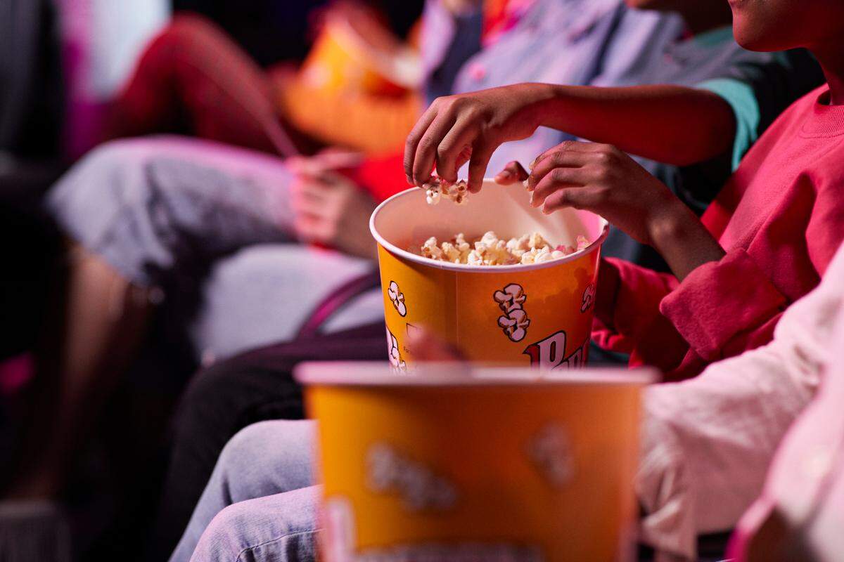 Friends sharing popcorn in a movie theater.