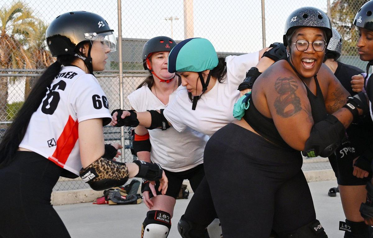 Maria “Kourt-knee Kar-Bash-U-In” Lewis, center, sneaks past Jessica “Afrodisiac” Meredith, right, during Ash City’s practice Thursday, May 6, 2025, in Fresno, California.