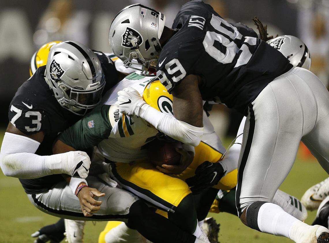 Green Bay Packers quarterback Brett Hundley, center, is sacked by Oakland Raiders defensive tackle Maurice Hurst (73) and defensive end Fadol Brown, hidden, during the first half of an NFL preseason football game in Oakland, Calif., Friday, Aug. 24, 2018. Also pictured is Raiders defensive end Arden Key (99).