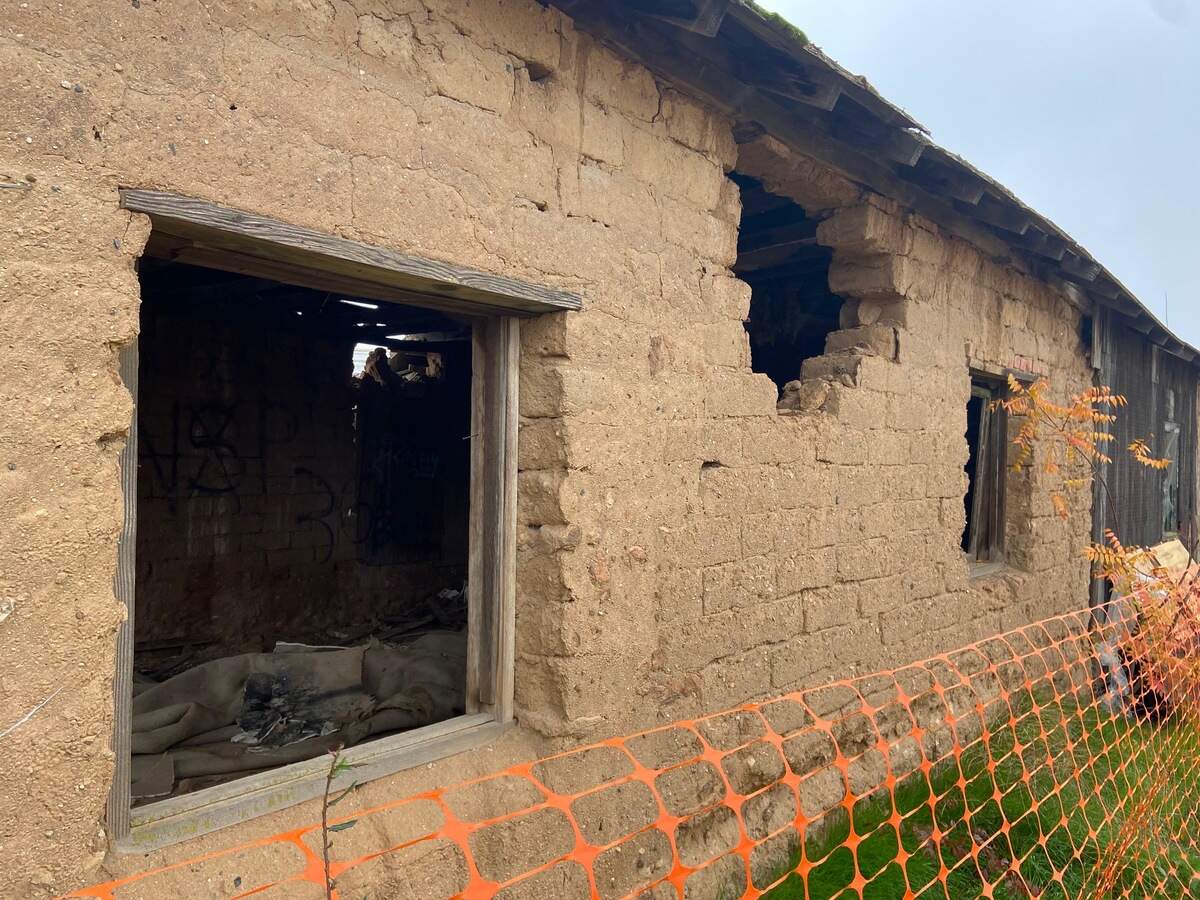 The Jose Garcia (Brewer) Adobe sits behind a plastic fence near Shaw Avenue west of Highway 99 in Fresno, California, on December 5, 2021. The adobe brick and hardpan structure, placed on the Local Register of Historic Resources in 1997, is under threat by a developer who originally requested its demolition.