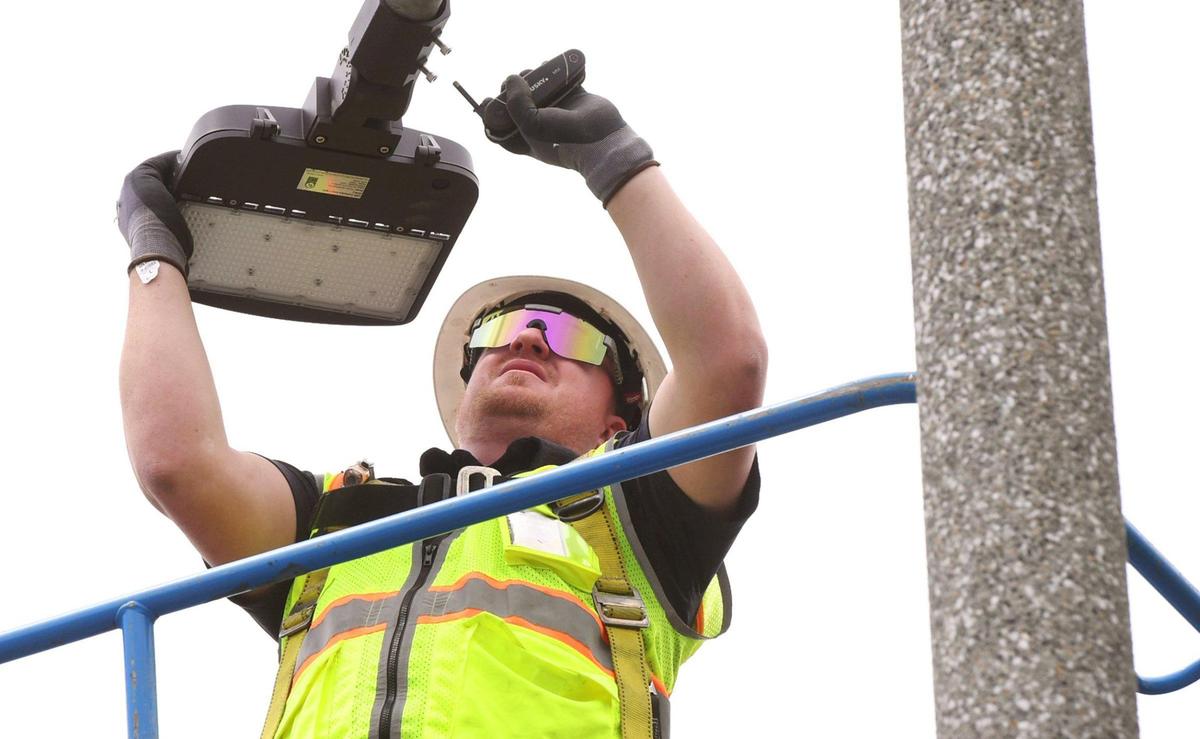 Alliance Building Solutions superintendent Cody Renwick perched on a lift about 30 feet in the air, installs an LED light on a post at Sunnyside Park after plans for a comprehensive city-wide energy project were announced at a press conference Tuesday, April 26, 2022 in Fresno.