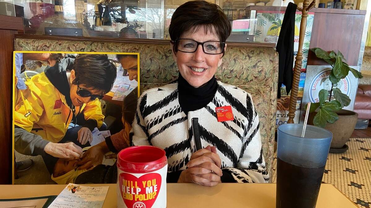 Singer, performer and Cultural Arts Rotary Club member Janice Noga, one of Fresno’s leading fundraisers for the polio vaccine, sits across the booth at Irene’s Cafe in the Tower District. At left is a photograph of Noga administering the vaccine to a baby during her 2024 trip to India.