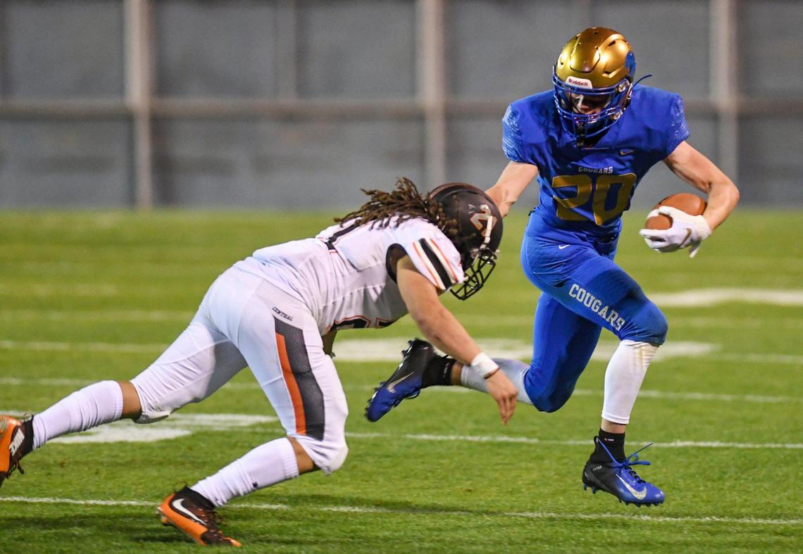 Clovis’ Tristan Risley, right, stiff-arms his way past the dive of Central’s Jaden Bonds during their game at Lamonica Stadium in Clovis on Thursday, March 18, 2021.