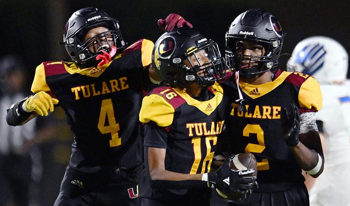 Tulare Union's Kamile Stevenson, left, and Franklin Lockard, right, celebrate Jaylon King, center, after King recovered a Bakersfield Christian fumble Friday, Sept. 26, 2025 in Tulare. Bakersfield Christian beat Tulare Union 30-7.