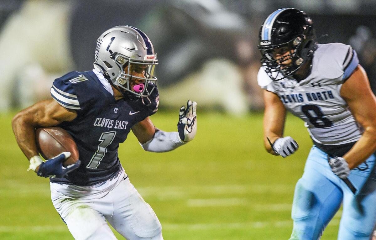 Clovis East’s Tommy Nix, left, takes the ball to the outside and looks to push his way past Clovis North’s Brayden Bitter during their TRAC opener at Lamonica Stadium on Friday, Sept. 29, 2023.