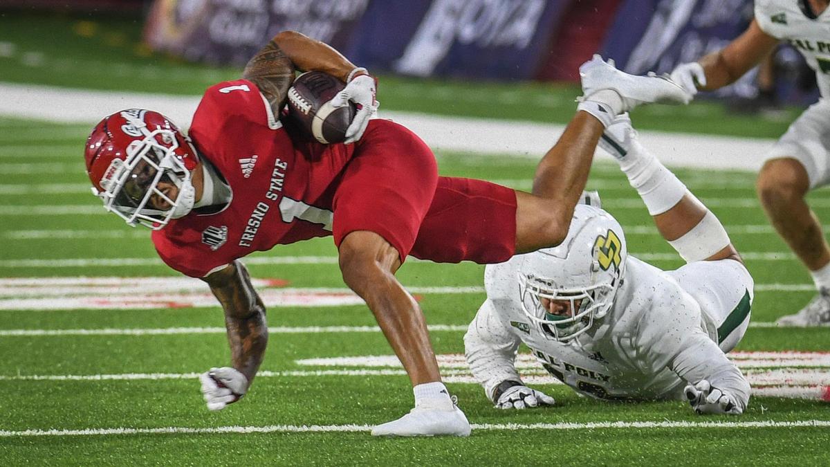 Fresno State’s Nikko Remigio left gets past a Cal Poly defender for a few more yards during their game at Valley Children’s Stadium on Thursday, Sept. 1, 2022.