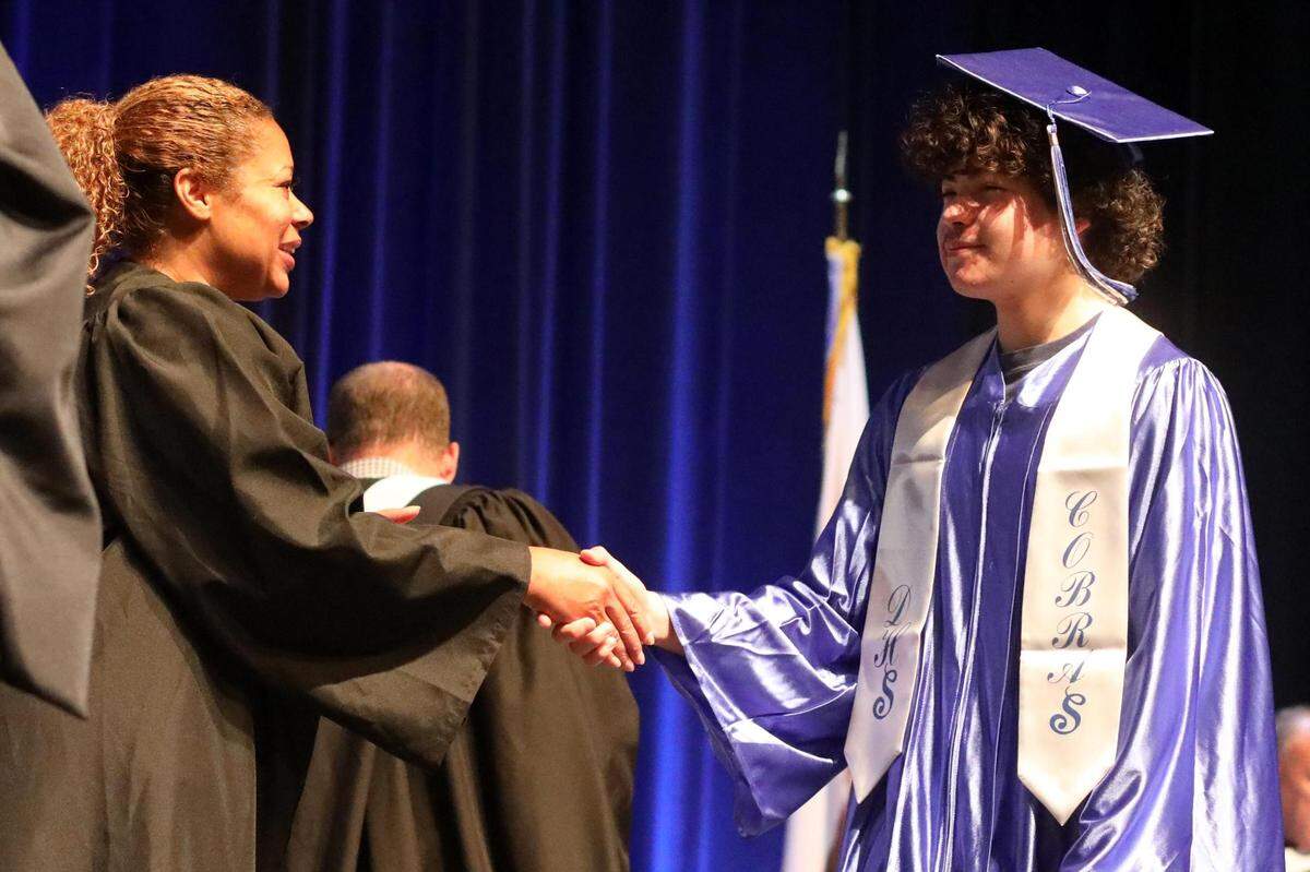 Keshia Thomas,  integrante de la junta directiva del Distrito Escolar Unificado de Fresno, con uno de los alumnos del último curso de DeWolf High School, durante la ceremonia de graduación de verano en el Audra McDonald Theater de Roosevelt High School, el viernes por la mañana.