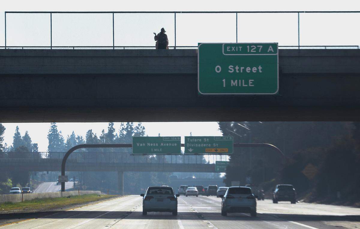 Cheryl “Monique” Turks, 47, of Fresno, waves from the Belmont Avenue overpass at Highway 41 in Fresno on Wednesday, Jan. 2, 2019.