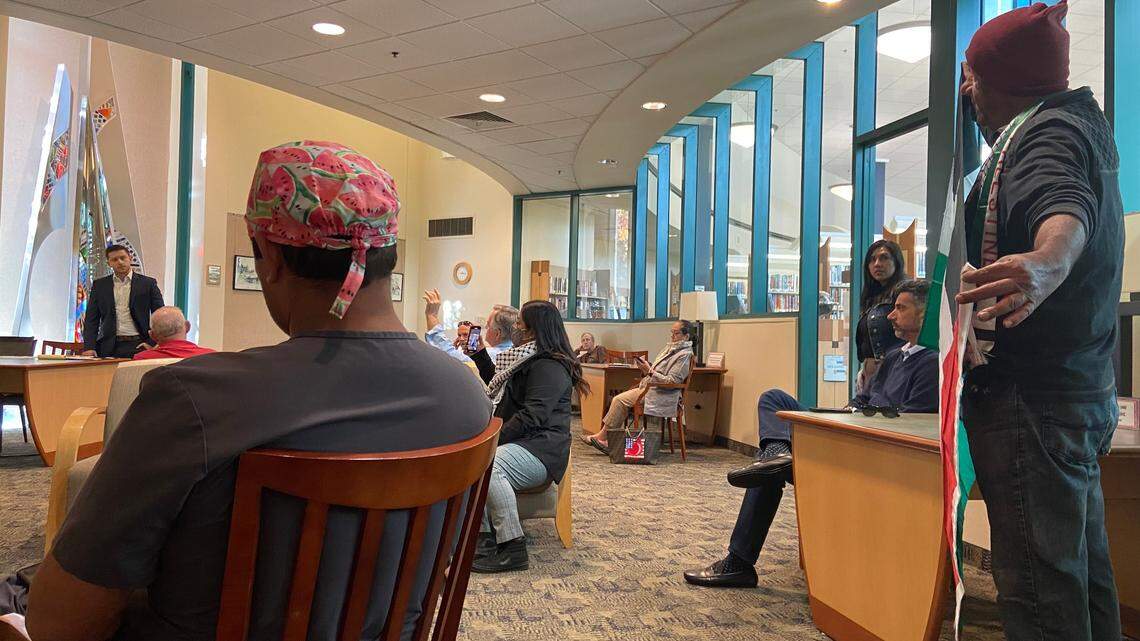 Brixton Layne, back left, a deputy constituent services director for Congressman Tom McClintock, listens as a man displaying a Palestinian flag, right, speaks during a staff office hours session at Woodward Park Regional Library in northeast Fresno on Wednesday, Nov. 8, 2023.