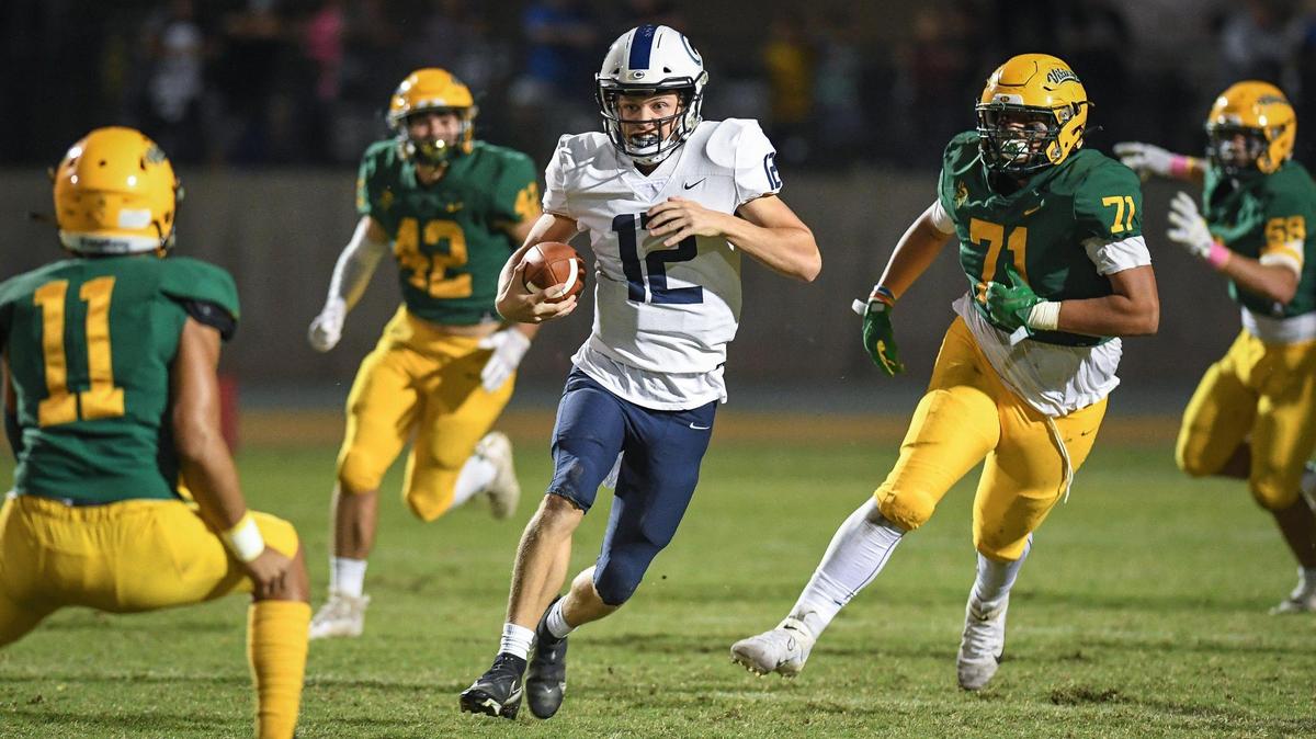 Central Valley Christian quarterback Max Bakker, center, scrambles through the Kingsburg defense on a run up the middle during their game at Kingsburg on Friday, Oct. 14, 2022.