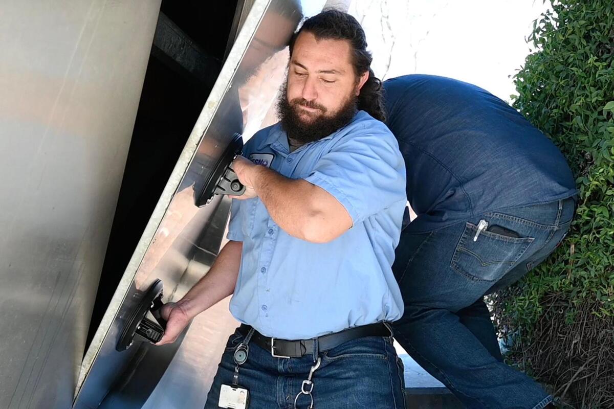 Denis Grider with the City of Fresno helps remove a panel to reveal a 30-year old time capsule locked inside a structural part of City Hall Tuesday, Dec. 13, 2022 in Fresno. A new time capsule will be locked away and retrieved in another 30 years.